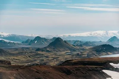 Highland view with snow patches, dark peaks and a distant glacier, taken on the Laugavegur in late July 2026